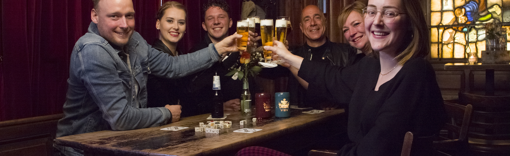 Een groep proost met een pilsje en lachen naar de camera